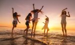 Group of happy young girls are having fun and dancing at sunset sea beach